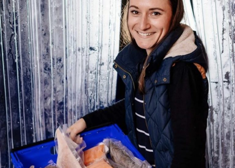 A woman holding a crate of fish
